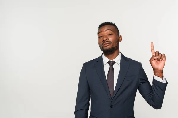 Hombre de negocios afroamericano en traje señalando con el dedo aislado en gris - foto de stock