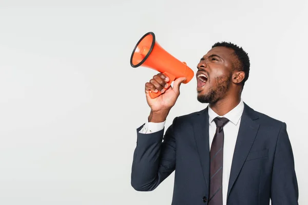 Hombre de negocios afroamericano en traje gritando en megáfono aislado en gris - foto de stock