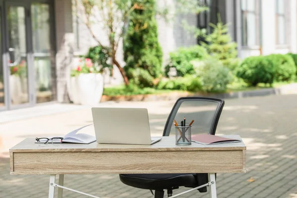 Portatile vicino notebook e cancelleria sulla scrivania fuori — Foto stock