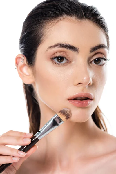 Mujer joven aplicando la base de la cara con cepillo cosmético aislado en blanco - foto de stock