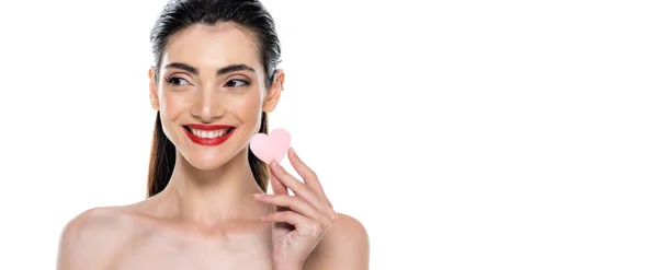 Femme positive avec des lèvres rouges tenant éponge de beauté en forme de coeur isolé sur blanc, bannière — Photo de stock