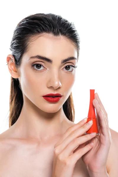 Morena mujer joven sosteniendo botella con esmalte de uñas naranja aislado en blanco - foto de stock