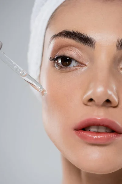 Close up of young woman applying vitamin c serum with pipette isolated on grey — Stock Photo