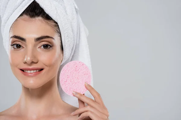 Felice giovane donna con asciugamano sulla testa in possesso di spugna rosa bellezza isolato su grigio — Foto stock