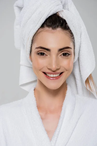 Happy young woman with towel on head smiling isolated on grey — Stock Photo