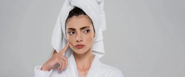 Pensive young woman with towel on head pointing at cheek isolated on grey, banner — Stock Photo