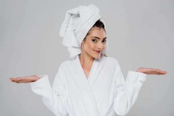 Pleased young woman with towel on head pointing with hands isolated on grey — Stock Photo