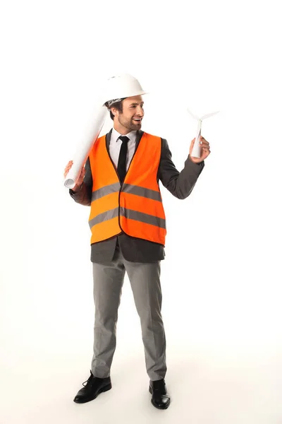 Ingeniero sonriente con plano mirando el modelo de turbina eólica sobre fondo blanco - foto de stock