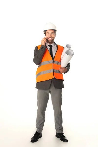 Ingeniero feliz tomando el teléfono móvil y sosteniendo planos sobre fondo blanco - foto de stock