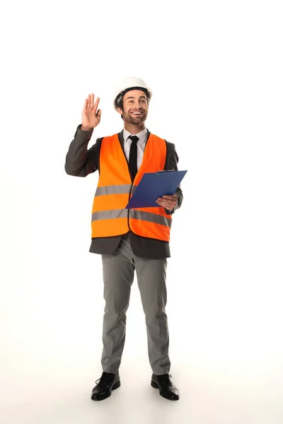 Smiling architect with clipboard waving hand on white background — Stock Photo