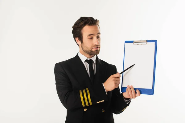 Young pilot pointing at clipboard isolated on white — Stock Photo