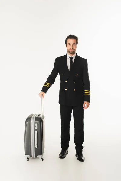 Young pilot with suitcase standing on white background — Stock Photo
