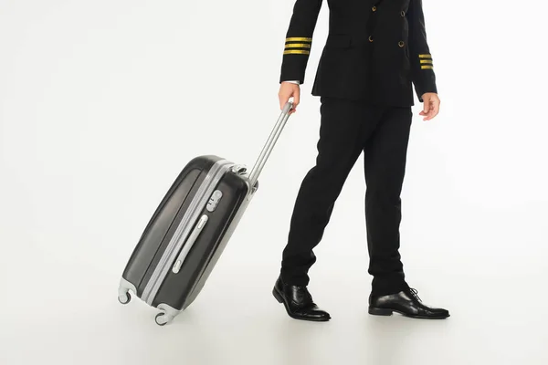 Cropped view of pilot with suitcase walking on white background — Stock Photo