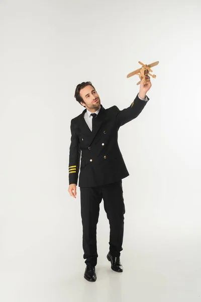 Full length of aviator holding wooden plane on white background — Stock Photo