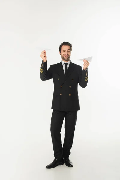 Piloto sorridente segurando aviões de papel em fundo branco — Fotografia de Stock