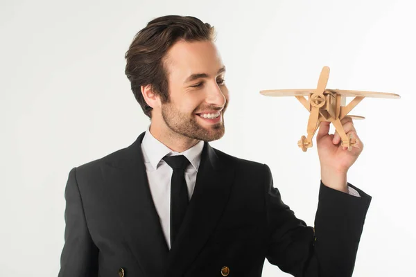 Fröhlicher Geschäftsmann blickt auf Holzflugzeug isoliert auf weißem Grund — Stockfoto