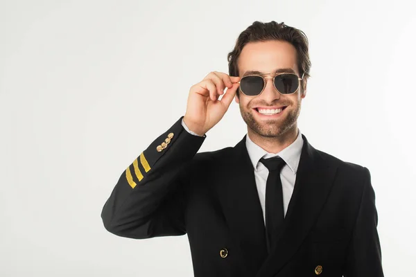 Aviador sonriente sosteniendo gafas de sol aisladas en blanco - foto de stock