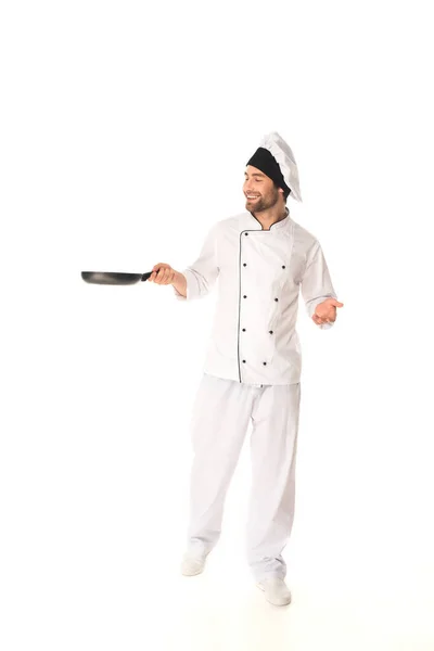 Smiling chef looking at frying pan on white background — Stock Photo