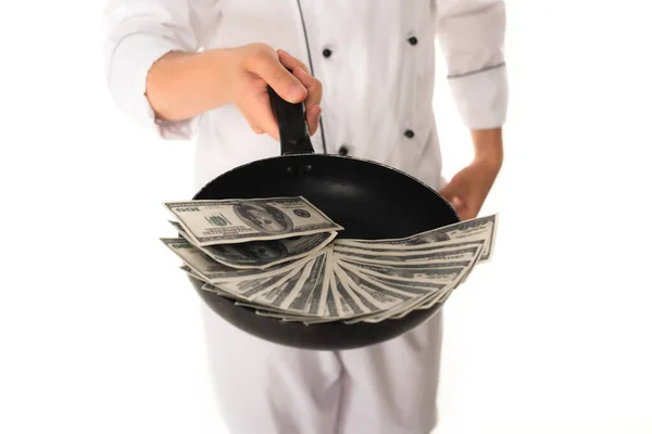 Обрізаний вид шеф-кухаря, що тримає сковороду з доларами ізольовано на білому — стокове фото