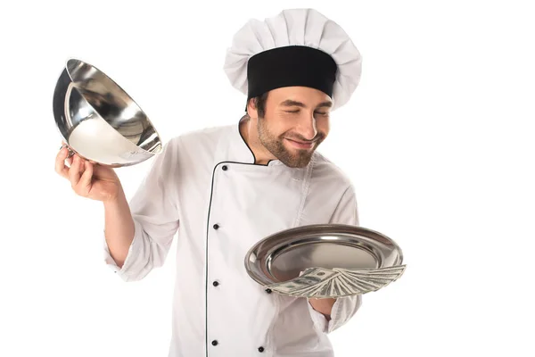 Улыбающийся шеф-повар, нюхающий деньги на подносе, изолированном от белого — стоковое фото