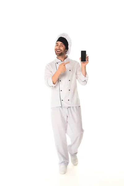 Chef sorridente che punta lo smartphone con schermo bianco su sfondo bianco — Foto stock