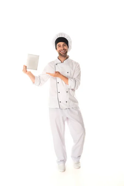Позитивний шеф-кухар вказує на цифровий планшет на білому тлі — стокове фото
