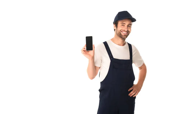 Smiling cleaner holding smartphone and hand on hip isolated on white — Stock Photo