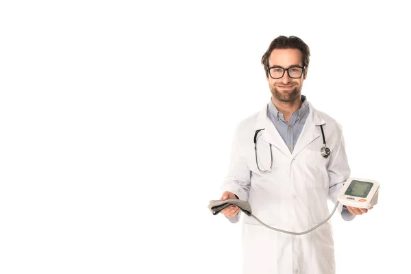 Улыбающийся доктор держит тонометр и смотрит на камеру, изолированную на белом — стоковое фото