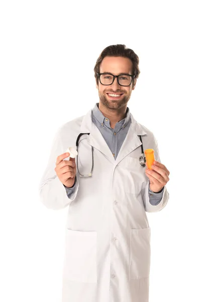 Позитивный доктор держит банку остроумия таблетки и колпачок изолирован на белом — стоковое фото