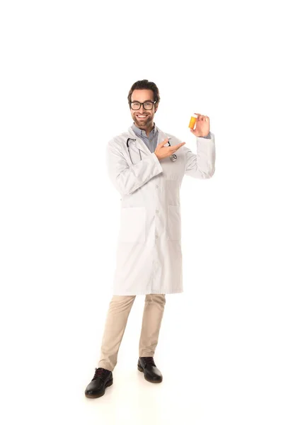 Улыбающийся доктор указывает на банку с таблетками на белом фоне — стоковое фото