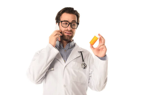 Médico falando no smartphone enquanto segurando pílulas isoladas no branco — Fotografia de Stock