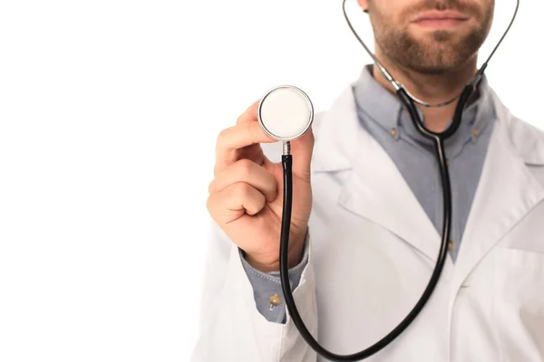 Vista recortada del doctor borroso sosteniendo estetoscopio aislado en blanco - foto de stock