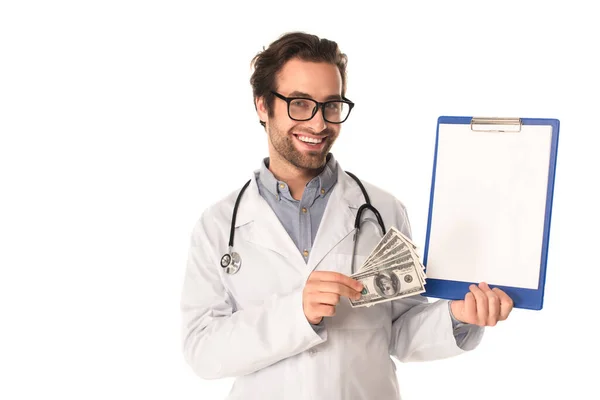 Молодой доктор держит деньги и буфер обмена с копировальным пространством изолированы на белом — стоковое фото