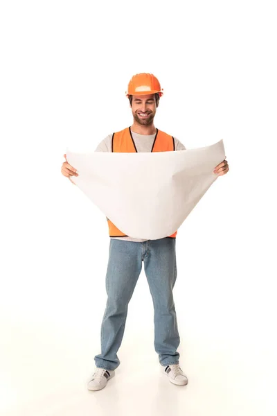 Full length of smiling builder looking at blueprint on white background — Stock Photo