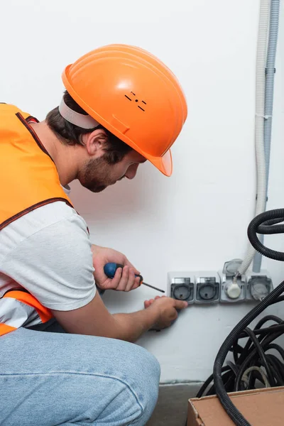 Seitenansicht des Arbeiters, der Schraubenzieher in der Nähe von Steckdosen hält — Stockfoto