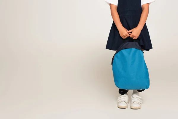 Vista cortada de estudante de pé com mochila azul no cinza — Fotografia de Stock