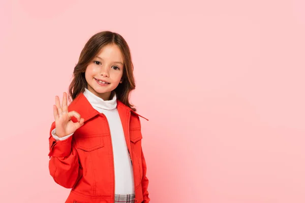 Ragazza elegante che mostra gesto ok mentre guarda la fotocamera isolata sul rosa — Foto stock