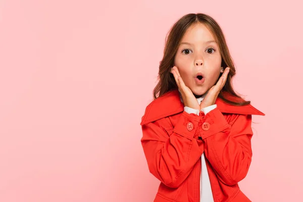 Stupito ragazza toccare il viso mentre guardando la fotocamera isolata su rosa — Foto stock