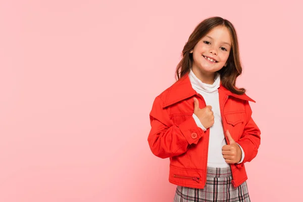 Cheerful girl in orange jacket smiling at camera isolated on pink — Stock Photo
