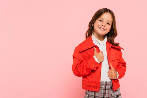 Gaie fille en veste orange souriant à la caméra isolé sur rose — Photo de stock