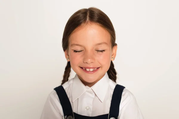 Довольный школьник улыбается с закрытыми глазами, изолированными на сером — стоковое фото