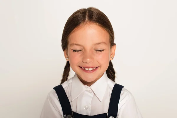 Niño contento sonriendo con los ojos cerrados aislados en gris - foto de stock