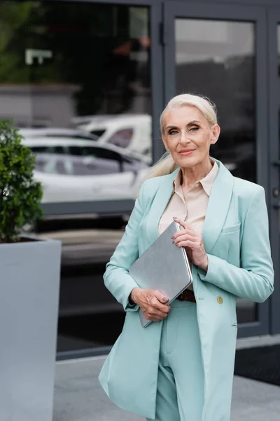 Senior businesswoman holding laptop outdoors — Stock Photo