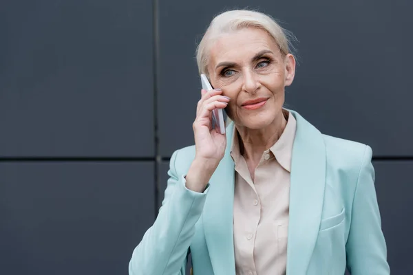 Ältere Geschäftsfrau spricht im Freien mit Smartphone — Stockfoto