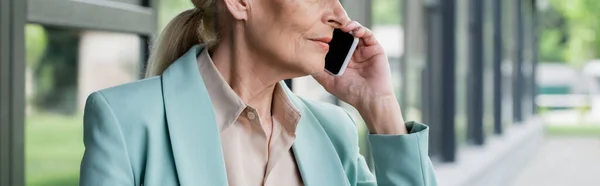 Cropped view of senior businesswoman talking on smartphone outdoors, banner — Stock Photo