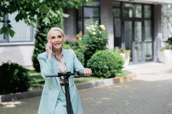 Senior businesswoman parler sur téléphone mobile près de scooter coup de pied électrique — Photo de stock