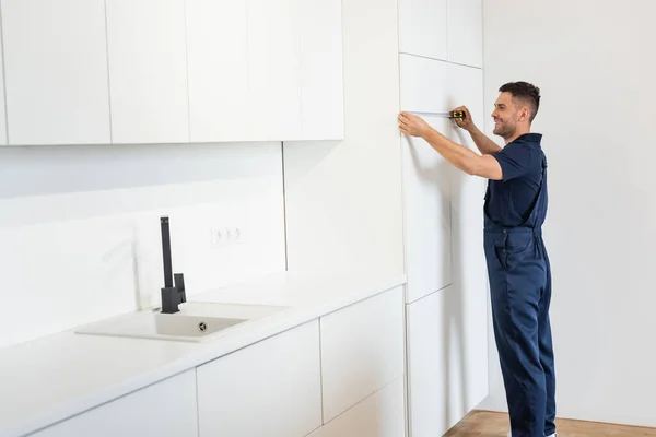 Heureux bricoleur meubles de mesure armoires dans la cuisine moderne — Photo de stock