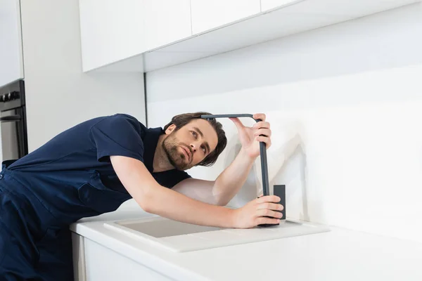 Klempner überprüft Wasserhahn in zeitgenössischer Küche — Stockfoto