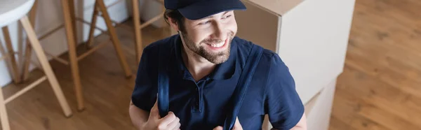 High angle view of smiling mover looking away near carton packages, banner — Stock Photo