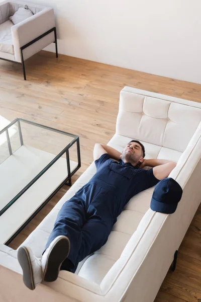 Високий кут зору виснаженого майстра спить на білому дивані — стокове фото